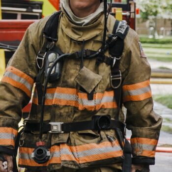 A firefighter in full turnout gear walks alongside a fire truck on scene