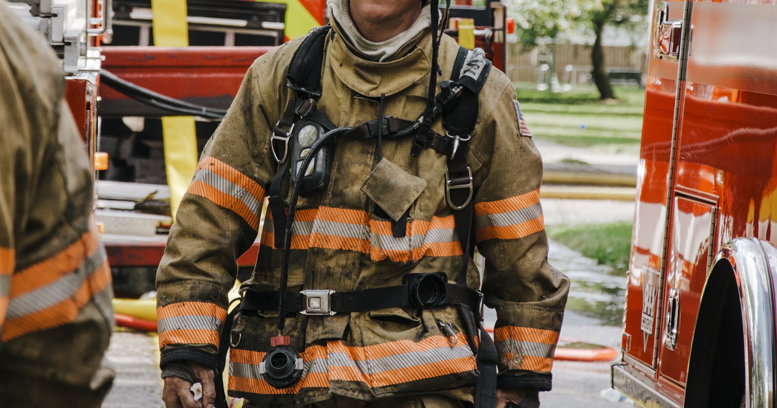 A firefighter in full turnout gear walks alongside a fire truck on scene